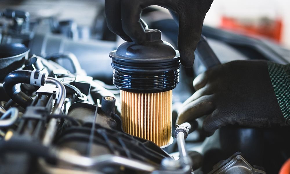 Best Oil Filter - hand removing oil filter from car's engine bay.
