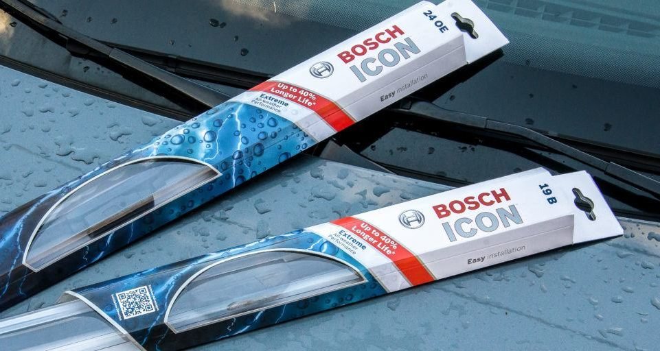 Pair of cased Bosch ICON wiper blades on car hood.